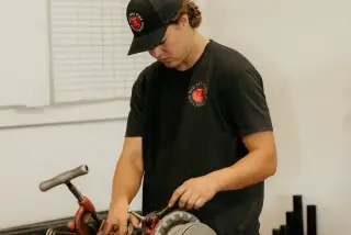 Red Seal technician preparing sprinkler pipe on a pipe machine.