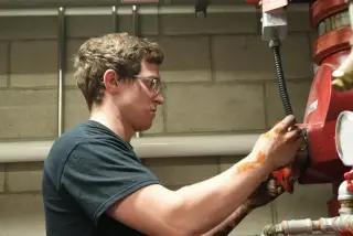 Red Seal technician turning a sprinkler control valve at a riser.